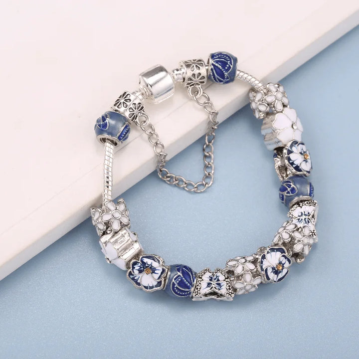 Silver butterfly charm bracelet with blue beads, white flowers, and a round clasp