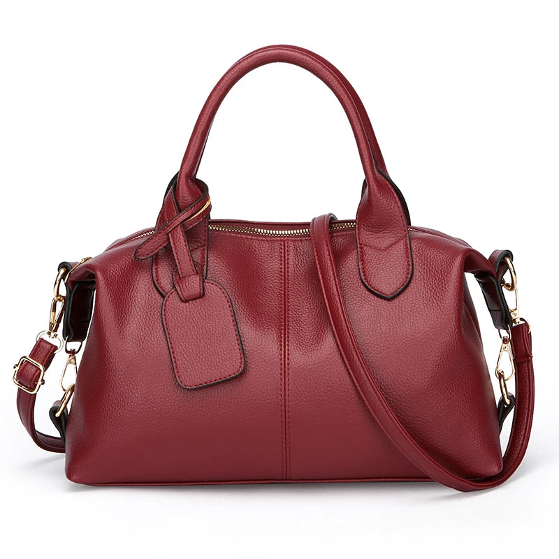 Women’s soft leather tote bag in burgundy red with top handles, zip closure, and crossbody strap