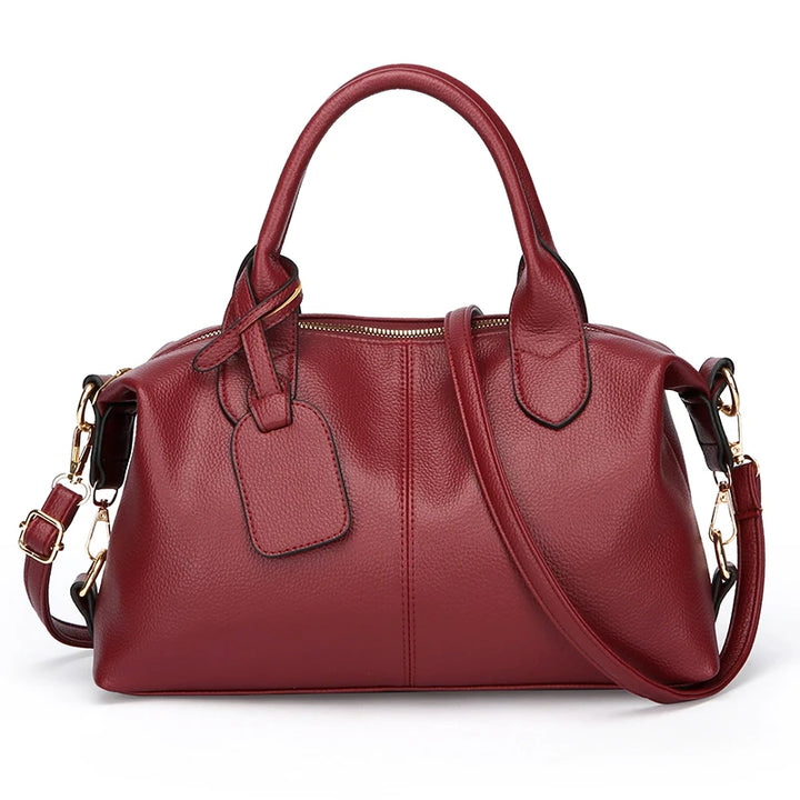 Women’s soft leather tote bag in burgundy red with top handles, zip closure, and crossbody strap