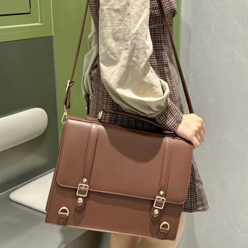 Brown crossbody bag with buckle straps and structured flap front