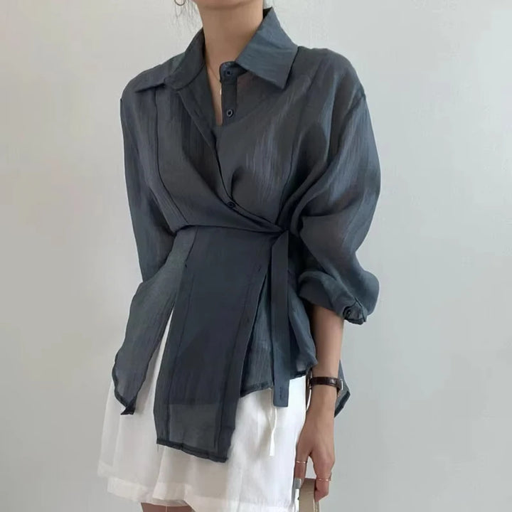 Person wearing a dark gray shirt over a white dress against a plain background