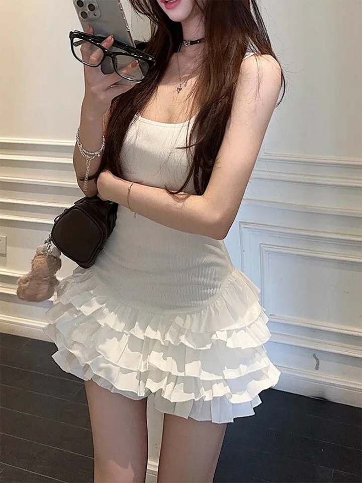 Woman in a white dress with ruffled layers taking a mirror selfie.