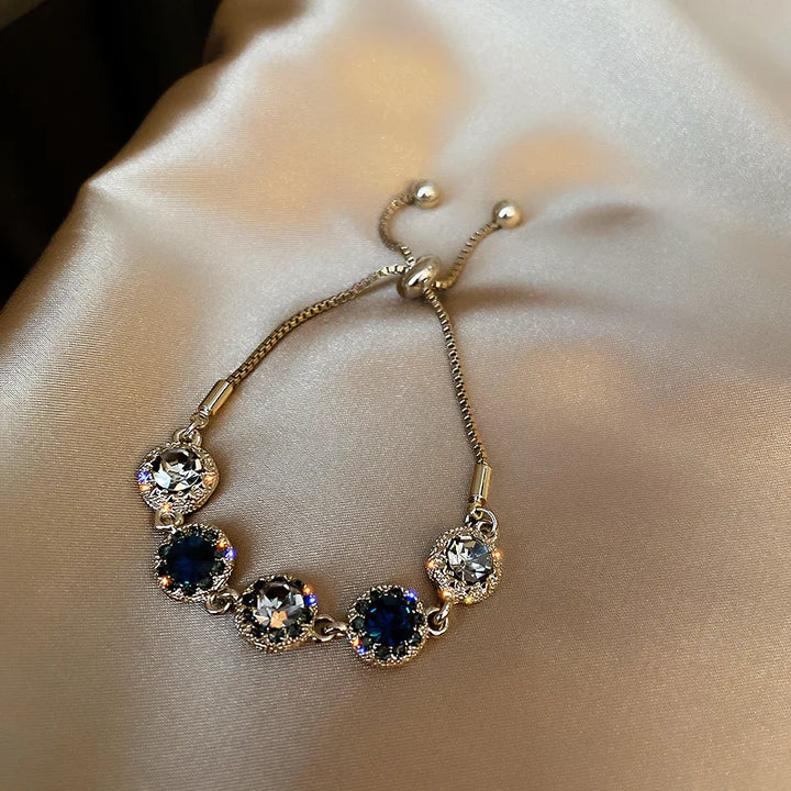 Gold-tone bracelet with round clear stones and dark blue center stones