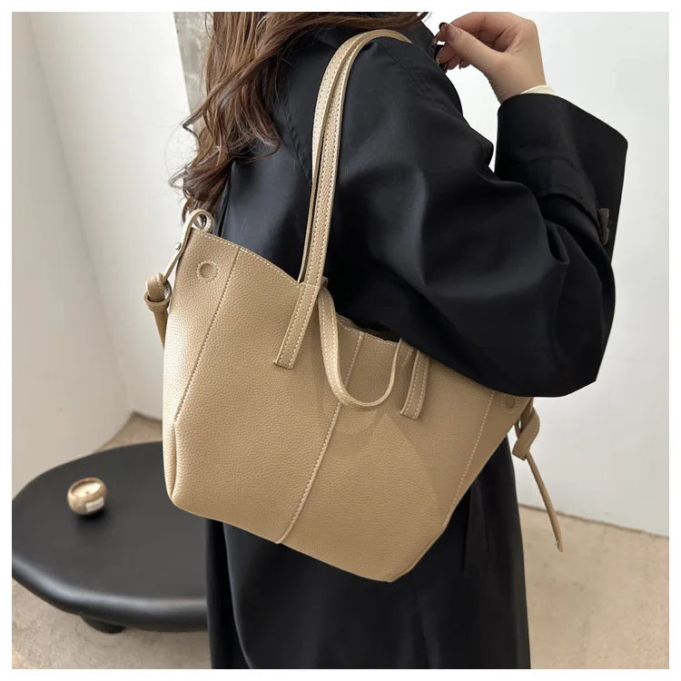 Person holding a beige handbag with a plain background