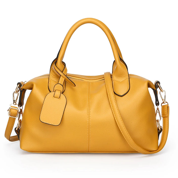 Yellow soft leather tote bag with top handles, front luggage tag, and crossbody strap