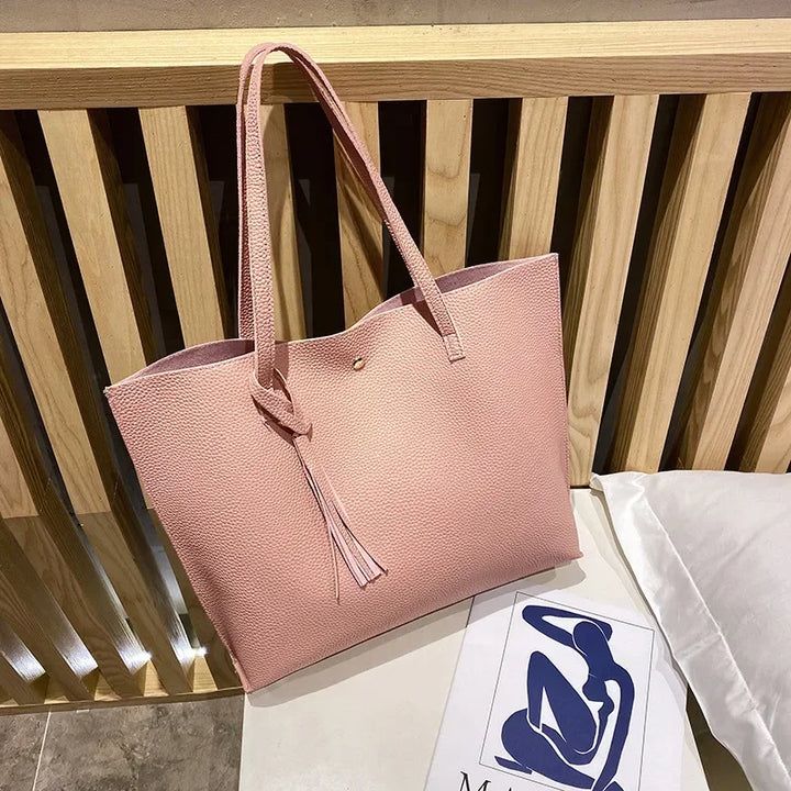 Pink tote bag on a wooden surface with a white pillow and blue design in the background