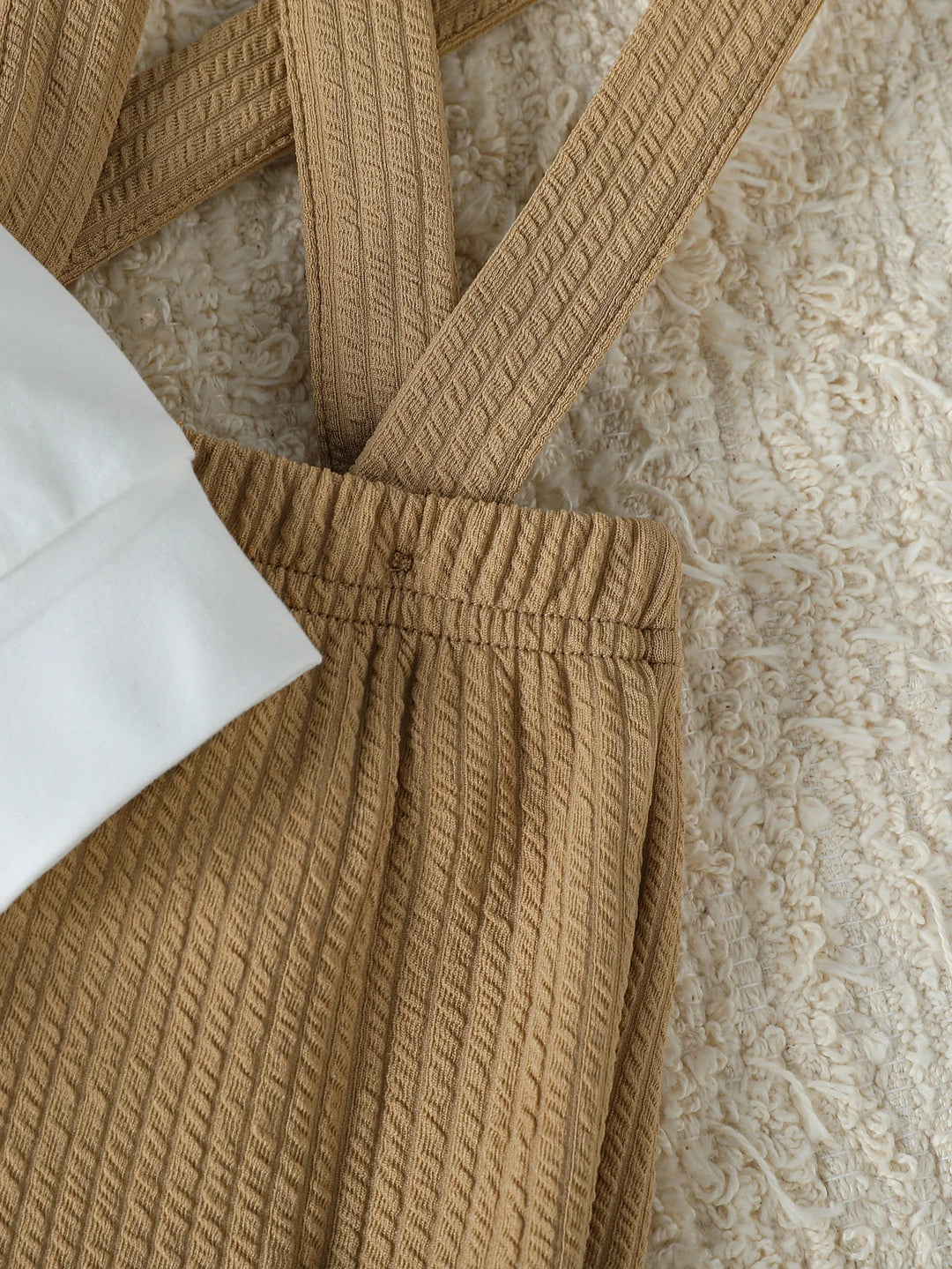 Close-up of a brown textured garment with a white fabric underneath on a neutral background