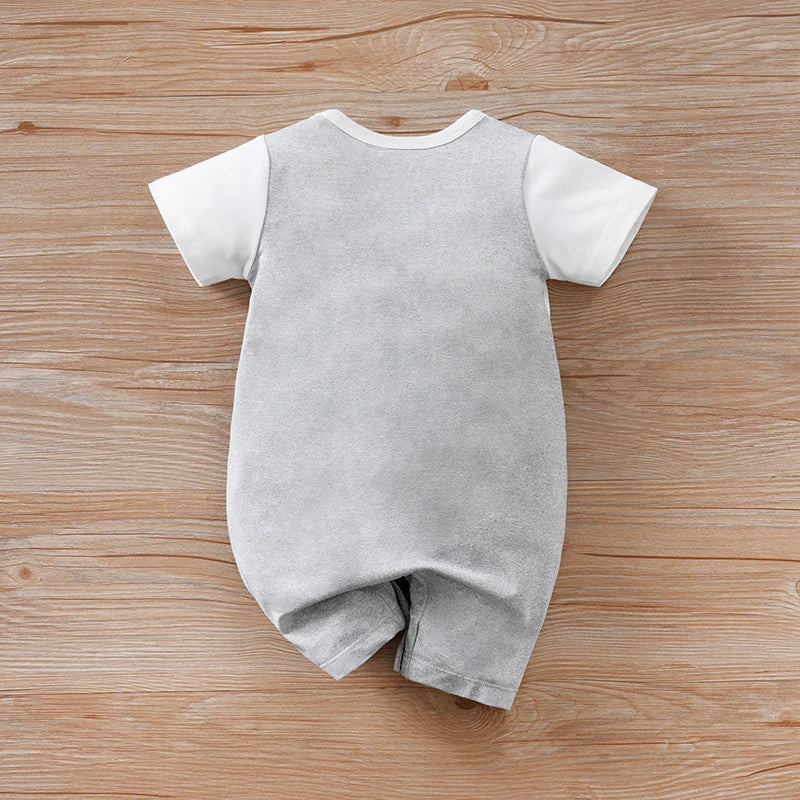 Gray baby romper with white sleeves on a wooden surface