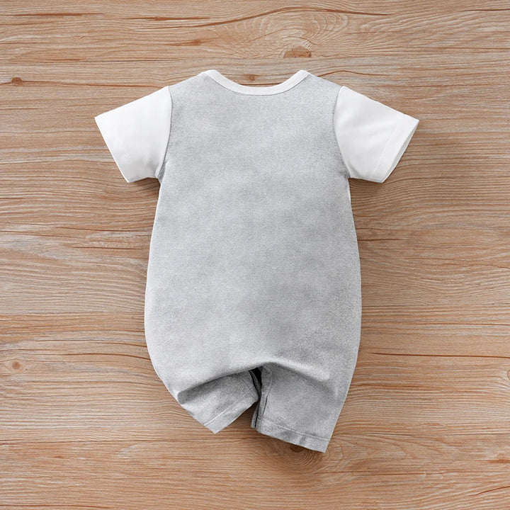 Gray baby romper with white sleeves on a wooden surface