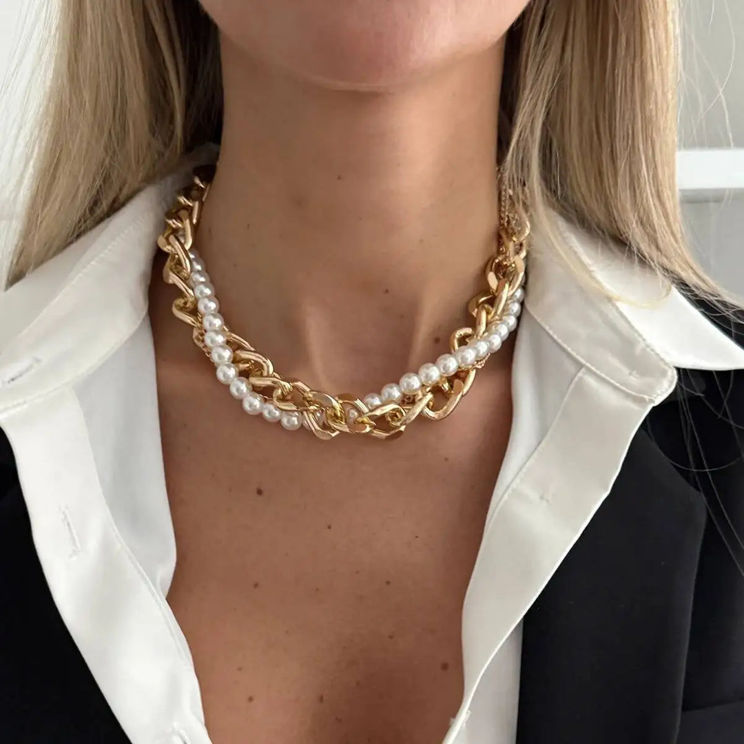 Gold chain and pearl necklace worn by a person with a blurred background