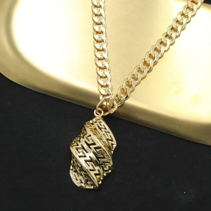 Gold chain necklace with a detailed pendant on a dark surface