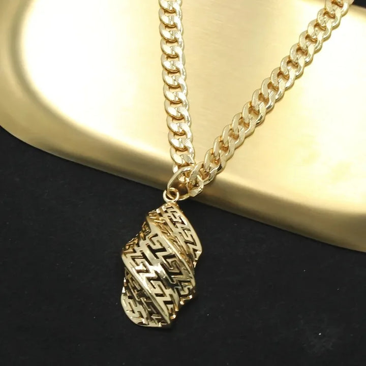 Gold chain necklace with a detailed pendant on a dark surface