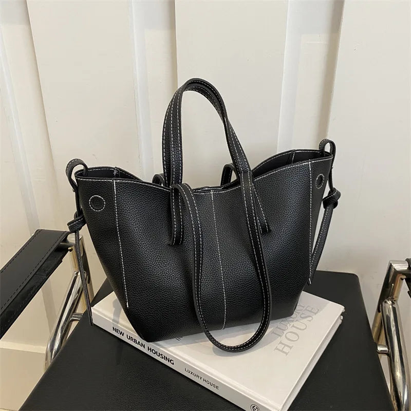 Black handbag on a book with a white curtain background