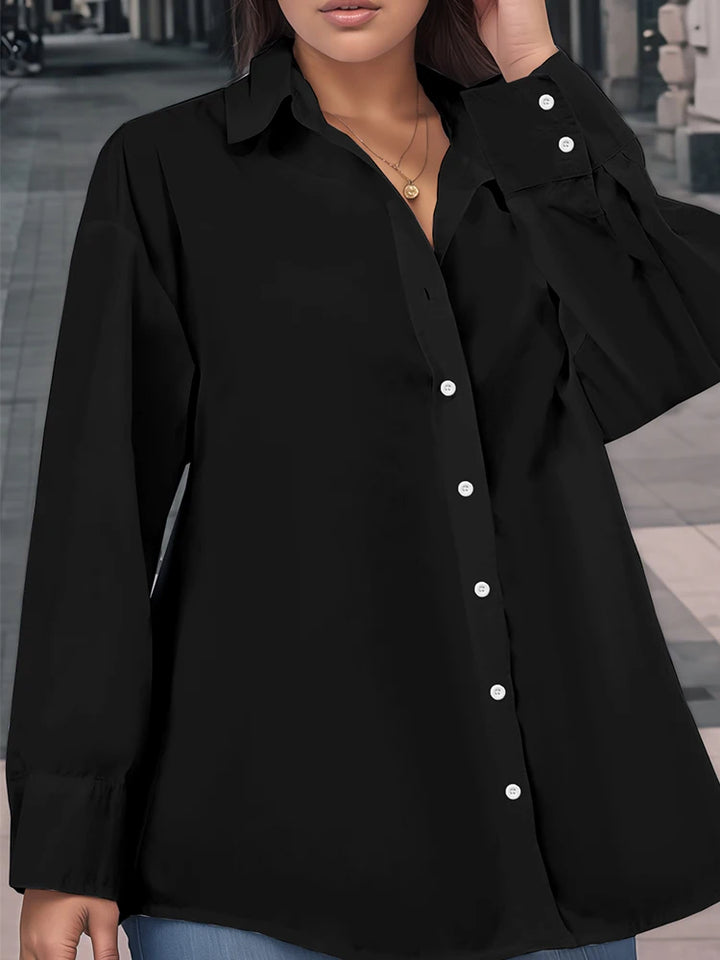Black button-up shirt worn by a person with a blurred indoor background