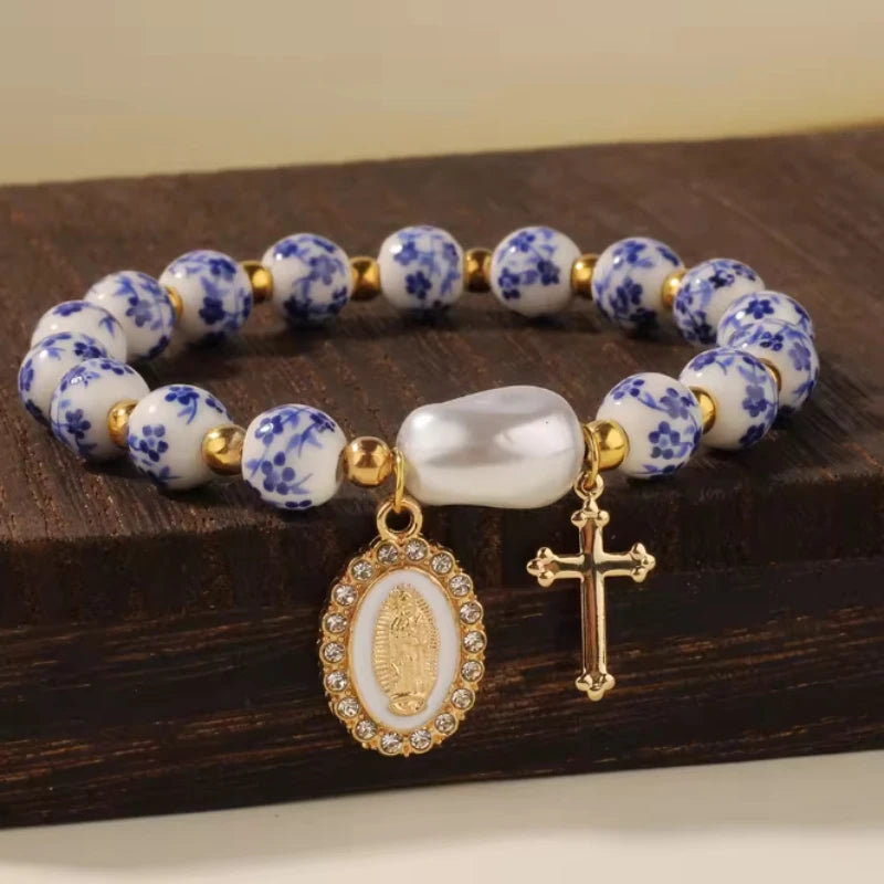 Bracelet with blue floral beads, gold accents, and religious charms on a wooden surface.