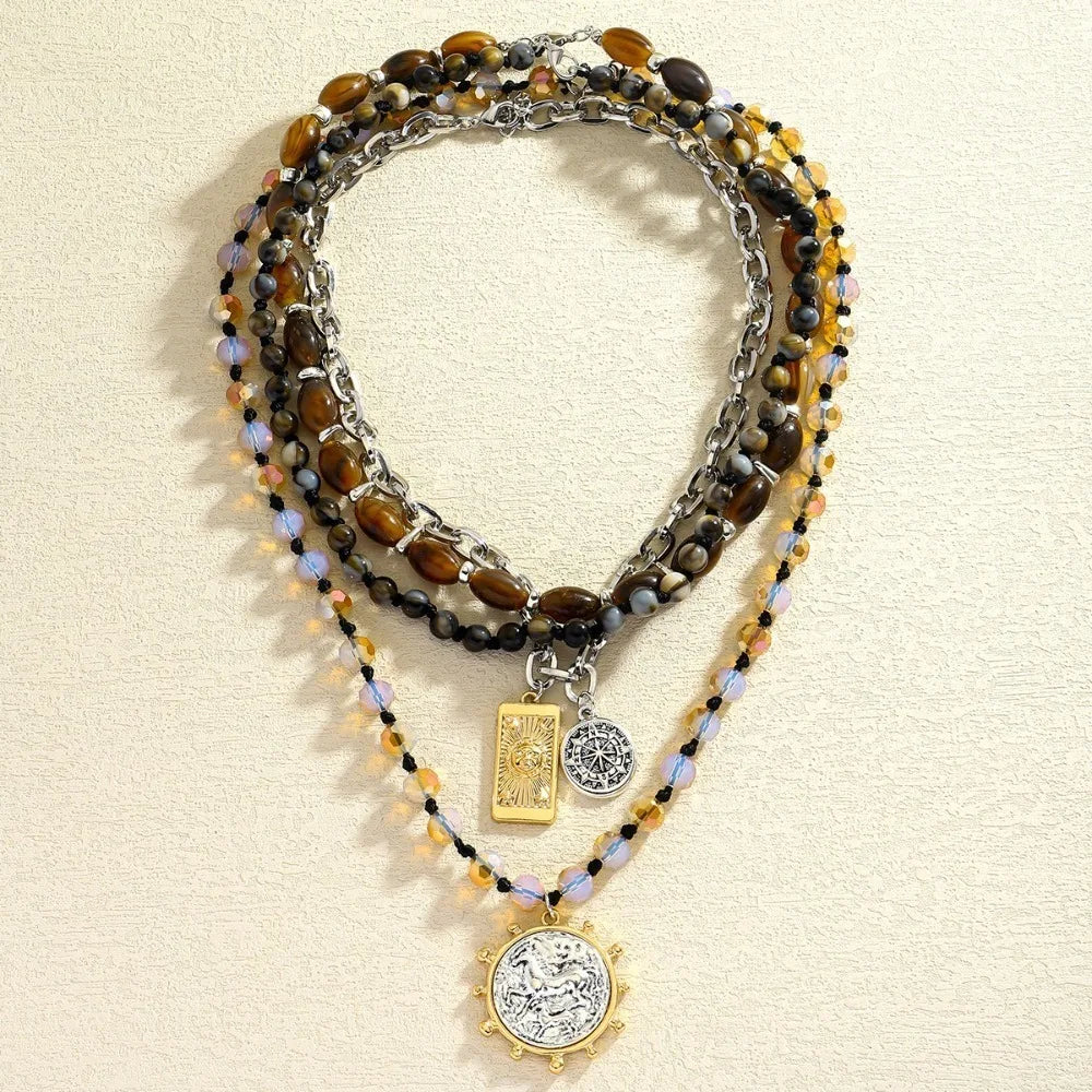 Beaded multi-strand necklace with dark beads and gold accents; square and coin charms pendant
