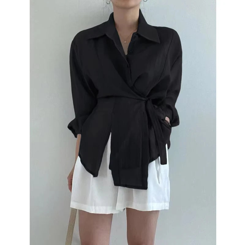 Person wearing a black shirt and white shorts against a plain background