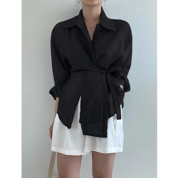 Person wearing a black shirt and white shorts against a plain background