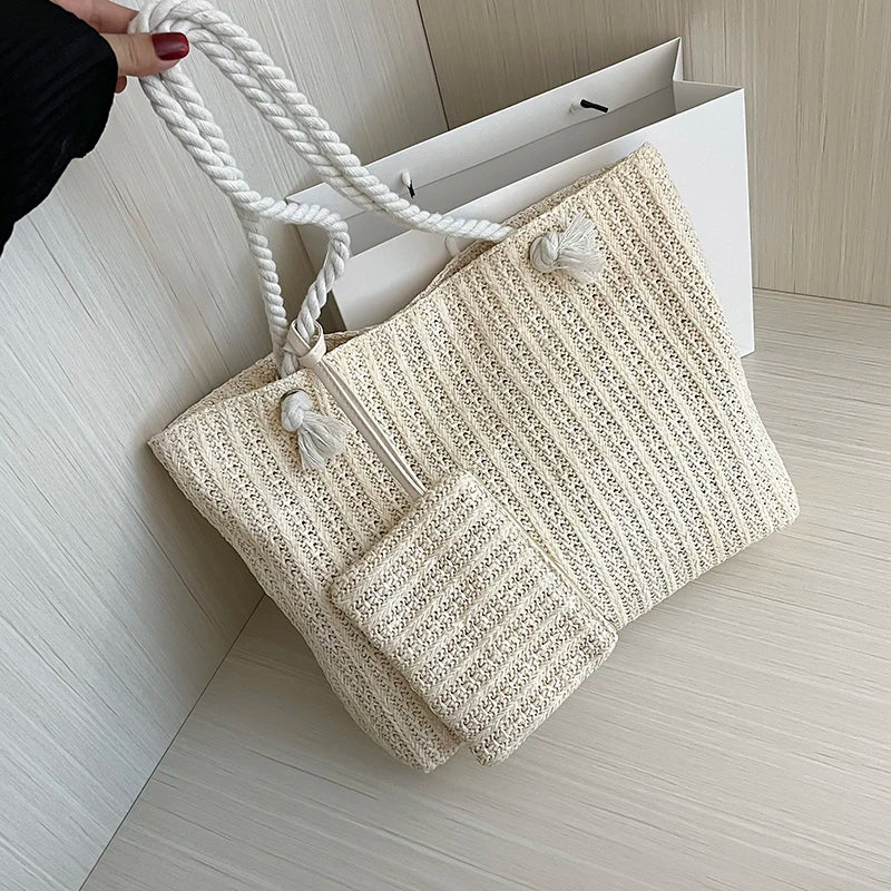 Beige woven handbag with rope handles on a light wooden floor.