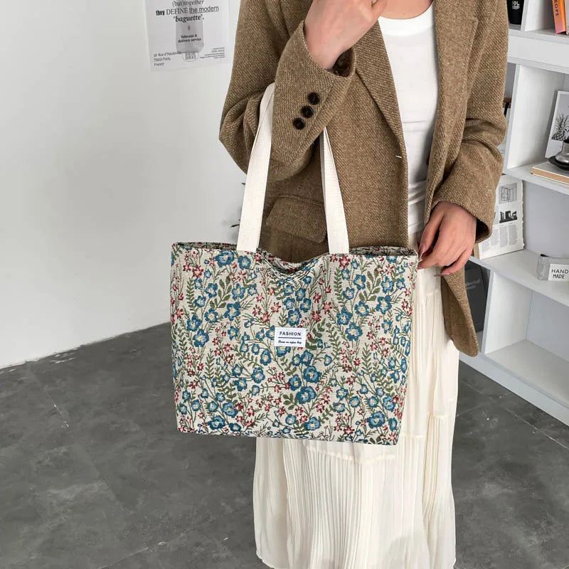 Canvas tote bag with blue floral and red accents, carried on white skirt