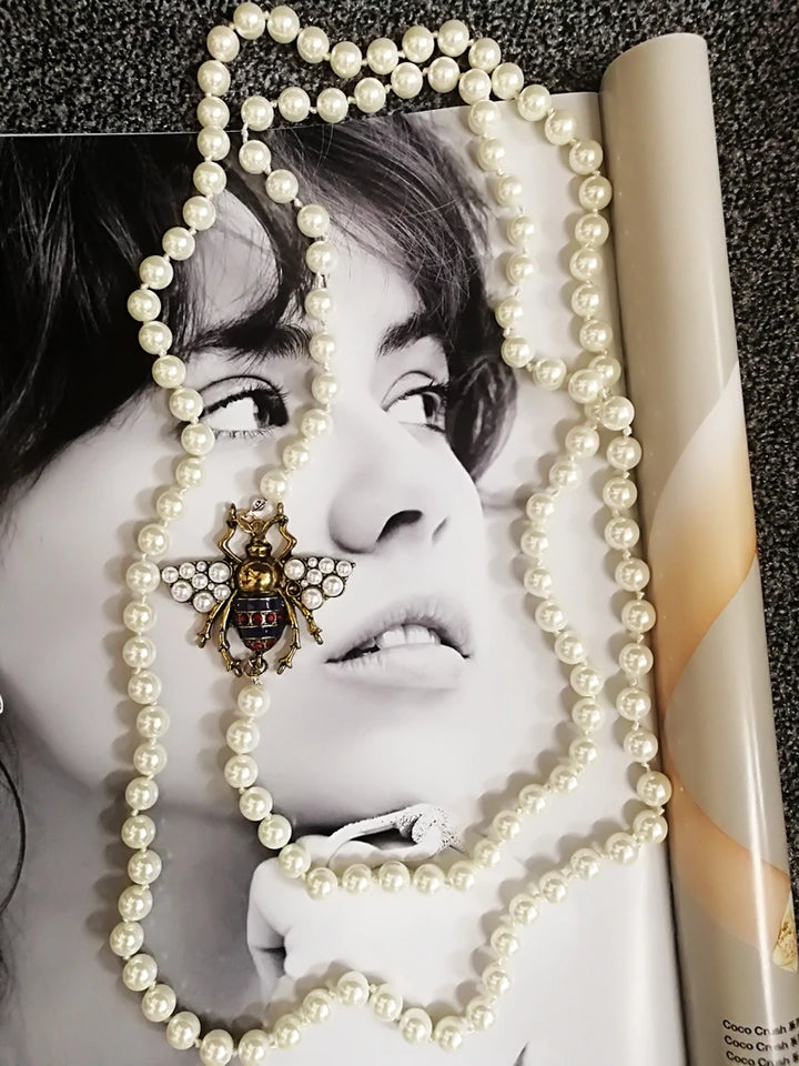 Pearl necklace draped over a magazine with a black and white photo of a person on the cover.