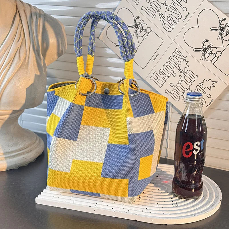 Yellow, blue, and white checker-block satchel bag with braided top handles.
