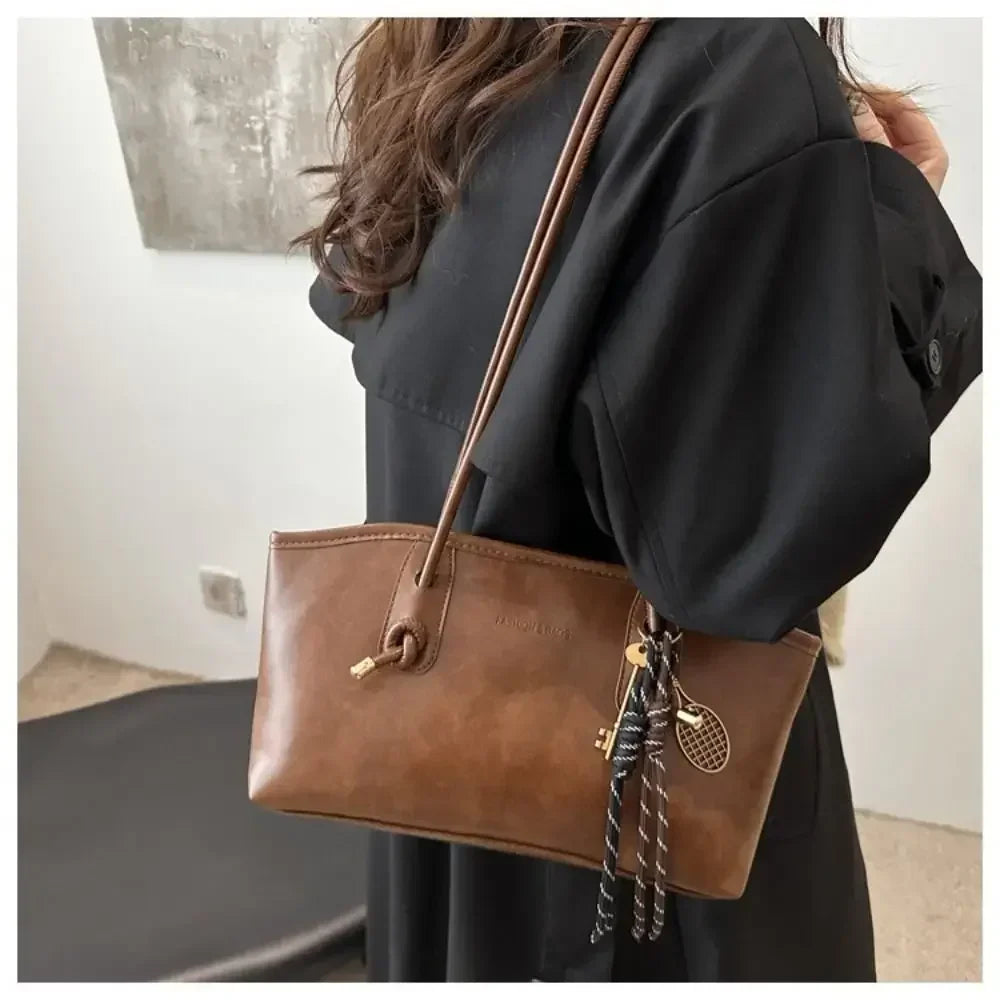 Caramel brown PU leather crossbody tote handbag on shoulder with braided tassel charm