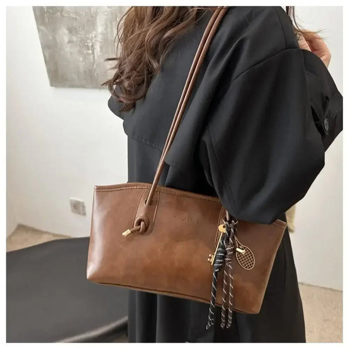 Caramel brown PU leather crossbody tote handbag on shoulder with braided tassel charm