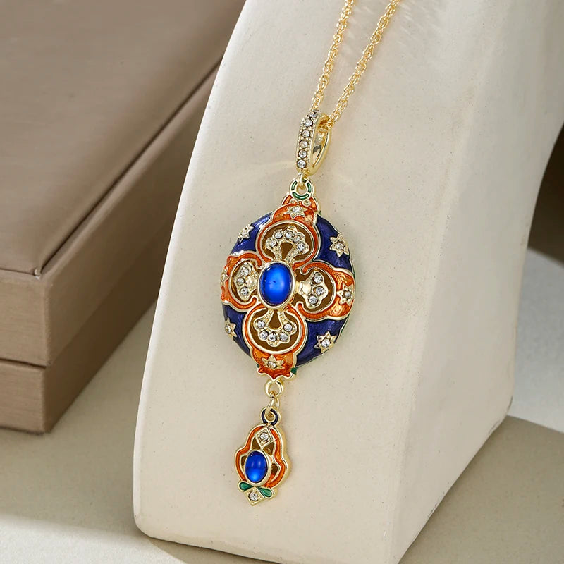 Decorative pendant necklace with blue gemstone on a white stand