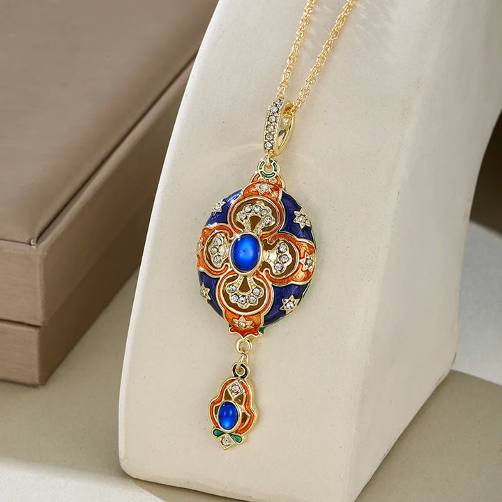 Decorative pendant necklace with blue gemstone on a white stand