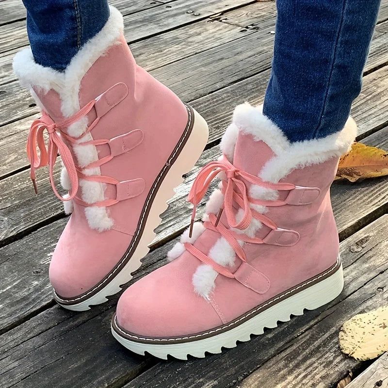 Pink winter boots with white fur lining worn on a wooden floor.