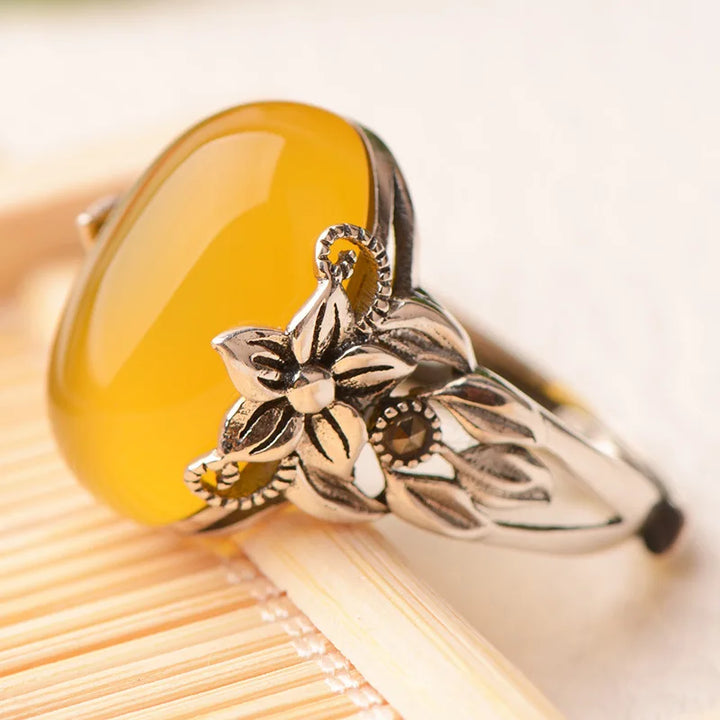 Silver ring with yellow stone on a wooden surface