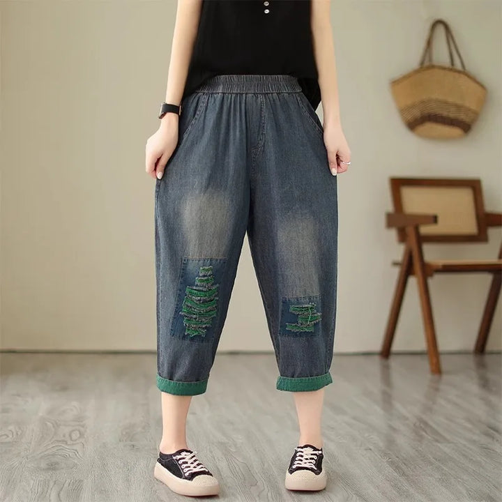 Person wearing patchwork denim pants with a minimal background