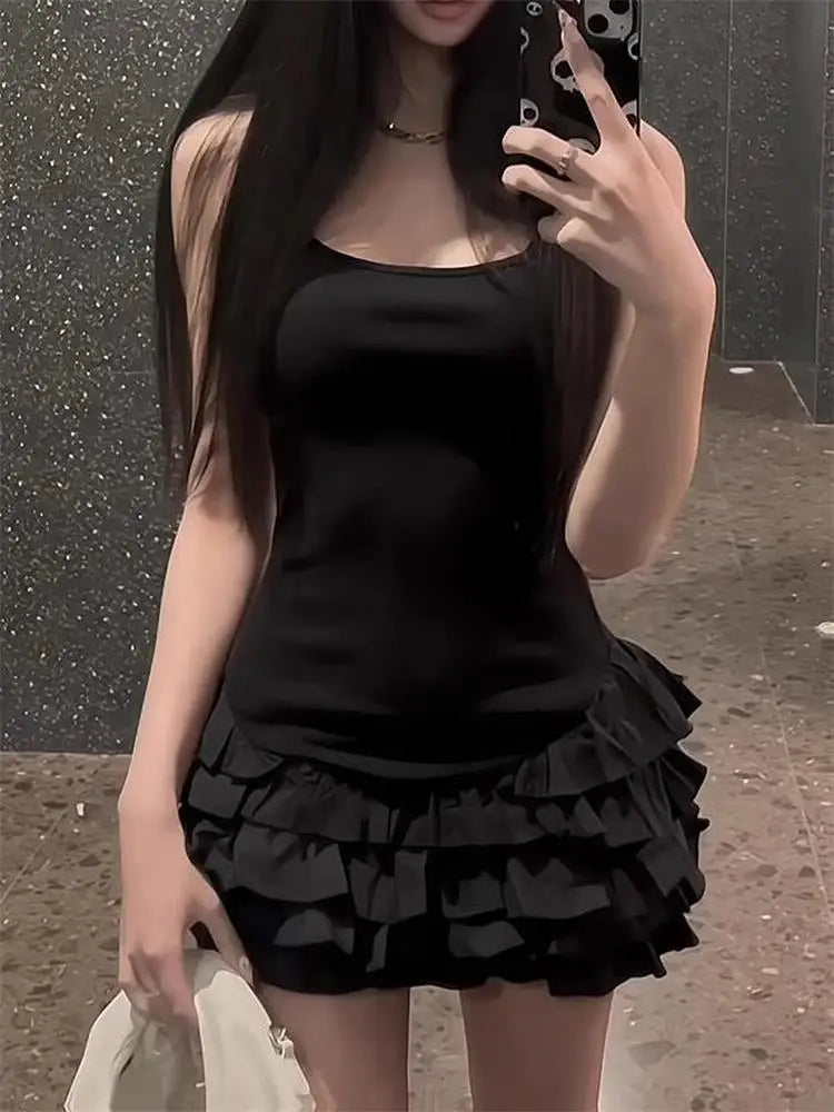 Person wearing a black sleeveless top and ruffled black skirt taking a mirror selfie.