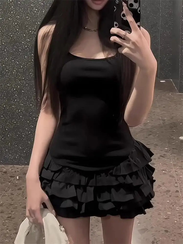 Person wearing a black sleeveless top and ruffled black skirt taking a mirror selfie.