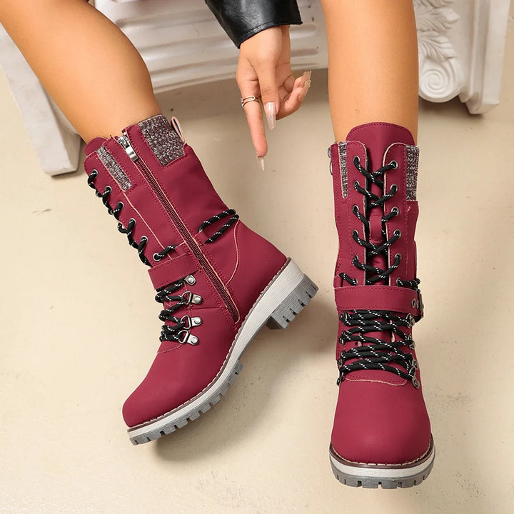 Women’s red lace-up winter boots with buckle strap and chunky non-slip tread sole.