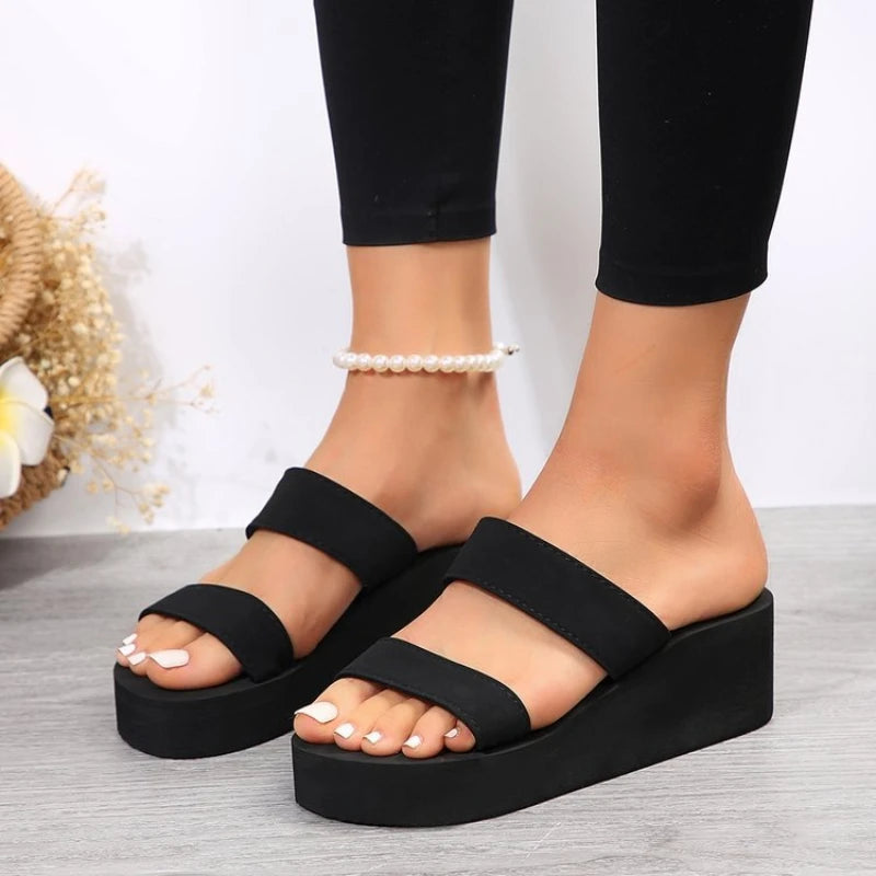 Black platform sandals worn with black leggings on a light background