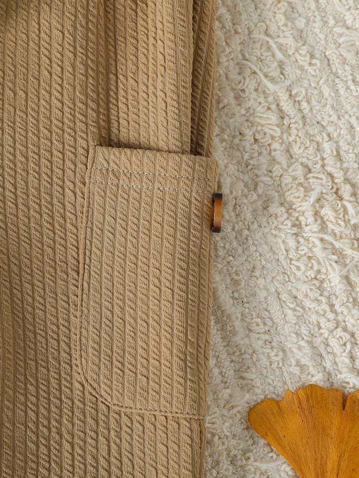 Close-up of a textured beige fabric with a wooden handle on a textured surface.
