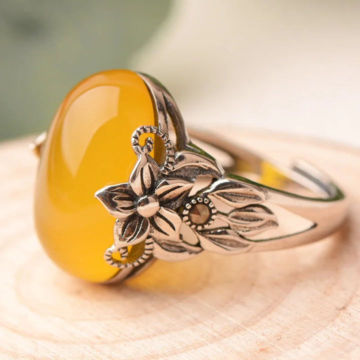 Ring with yellow stone and floral design on a wooden surface