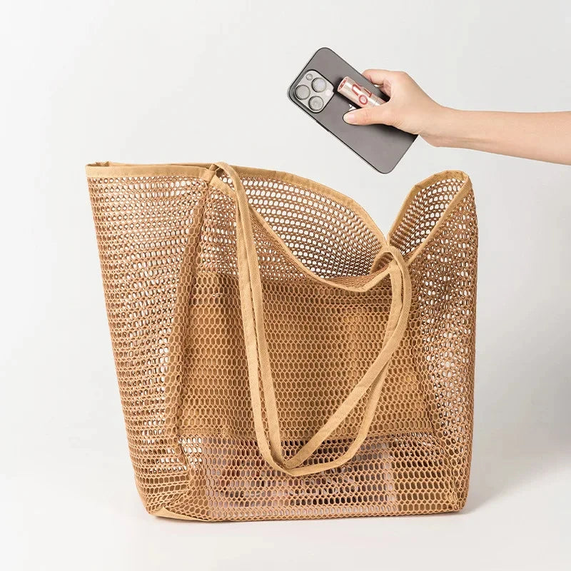 Mesh travel tote in tan with wide gusset base, open top, and shoulder strap