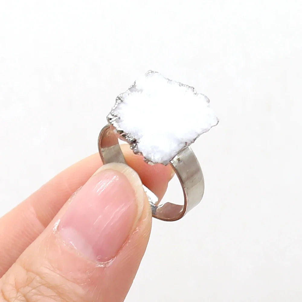 Gold ring with a large, clear crystal held by a hand against a white background