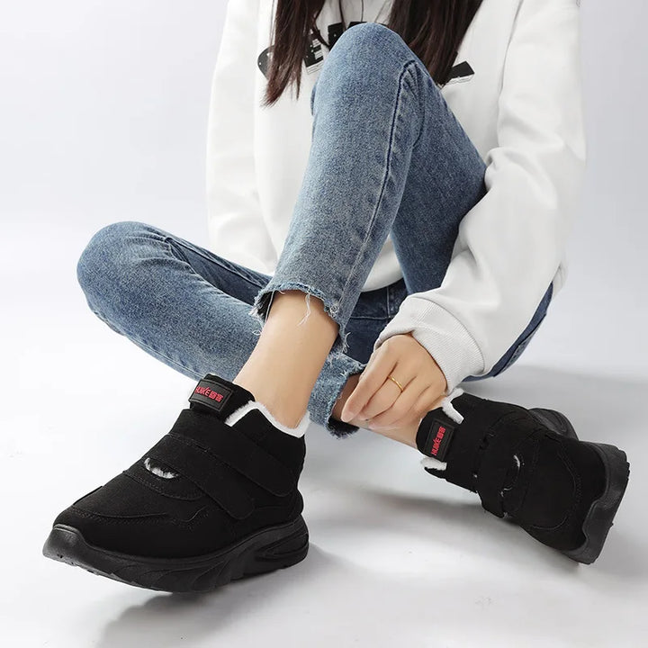 Person wearing black shoes with velcro straps on a white background