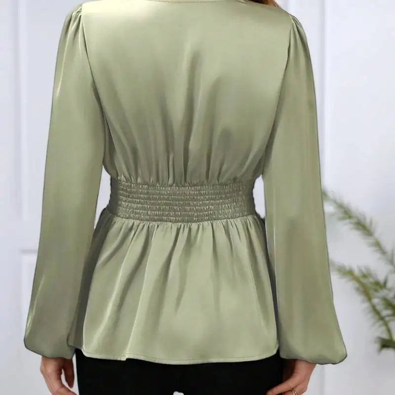 Green long-sleeve top worn by a person on a white background