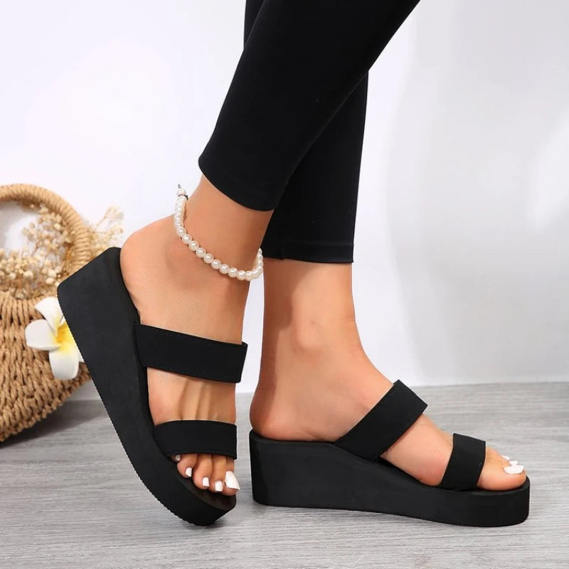 Black platform sandals worn with black leggings on a light background