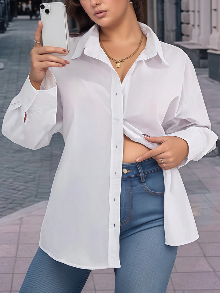 Person wearing a white shirt and blue jeans, taking a selfie on a street.