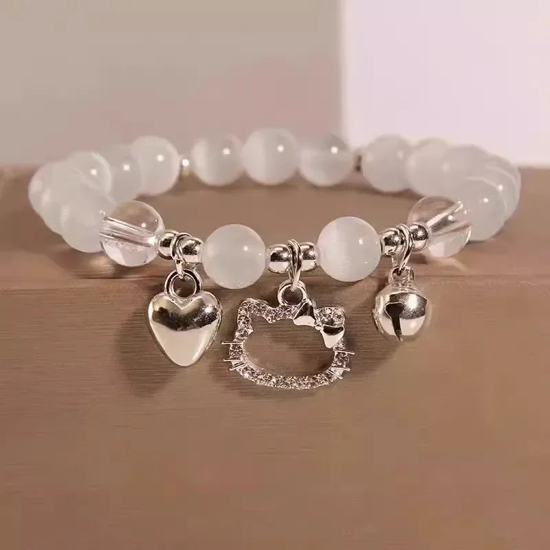 White bead charm bracelet with heart, star, and bell pendants on a wrist