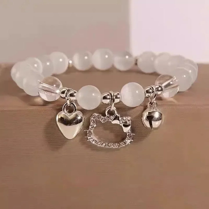 White bead charm bracelet with heart, star, and bell pendants on a wrist