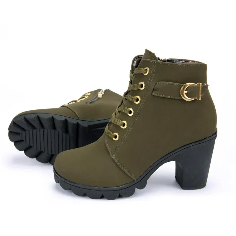 Pair of green ankle boots with gold buckles on a white background