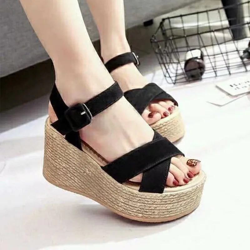 Black wedge sandals on a neutral background