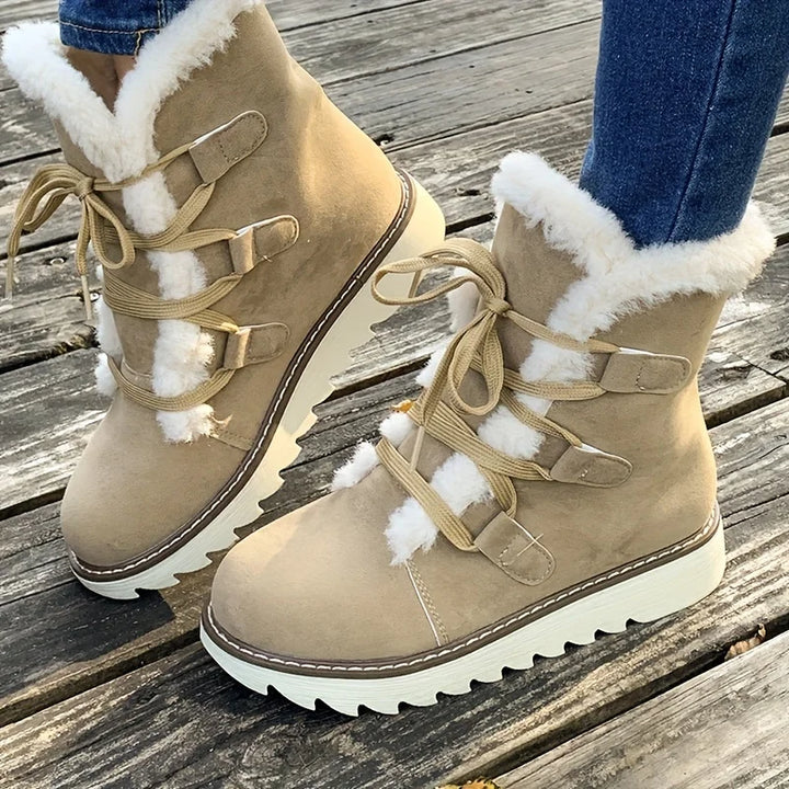 Beige winter boots with white fur lining on a wooden floor